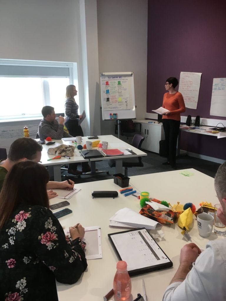 A view across the classroom of Natasha, one of our Talent Development Learners, presenting her six thinking caps presentation to the rest of her cohort.